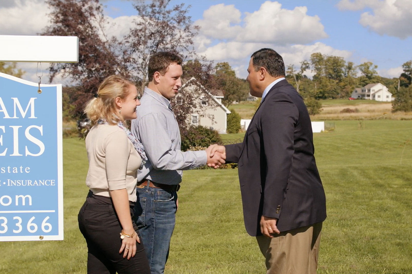 William Raveis BCK Real Estate agent shakes hands with clients.